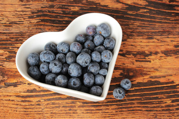 Heidelbeeen, Blaubeeren in herzförmiger Schale, Herz, Holztisch