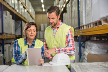 Man and a woman have short meeting in a warehouse and checking inventory levels of goods. First in first out, Last in last out, team working together concept photo. - obrazy, fototapety, plakaty