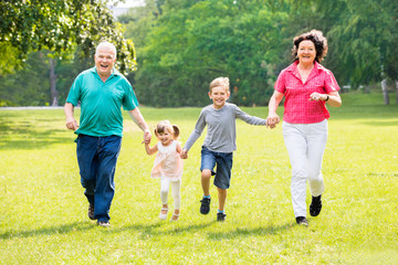 Fototapeta premium Grandparents And Grandchildren Running In Park