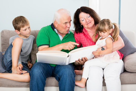 Grandparent And Grandchildren Looking At Photo Album