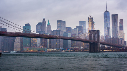 Timelapse day to night. Rainy Manhattan and the Brooklyn Bridge. The tops of the skyscrapers in...