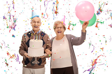 Overjoyed seniors celebrating a birthday with a cake and balloon