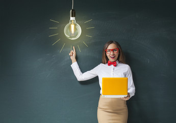 Young woman using a laptop and pointing on lightbulb