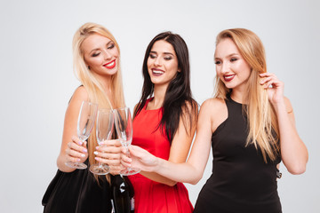 Three happy charming young women celebrating and drinking champagne together