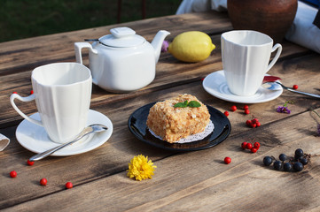 Cake on black plate and white tea pot served on wooden table 
