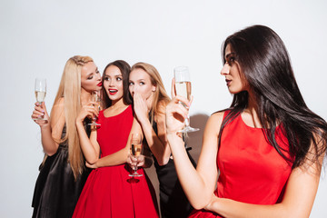 Smiling young women drinking champagne and gossiping on the party
