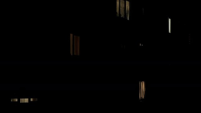 Time lapse of windows multistory apartment building during sunrise. Residents turn off the electric lights in the apartments.