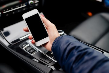 Woman using white smartphone in car.