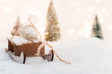 Small wooden sleigh with a Christmas tree in the snow