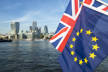 European Union and Union Jack flags flying over the London skyline of the financial City center at the River Thames