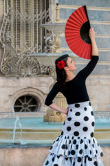 Young beautiful woman in a flamenco costume. Fountain on the background.  - obrazy, fototapety, plakaty