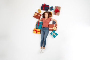 Young beautiful curly girl lying on floor among gift boxes Shot from above Isolated