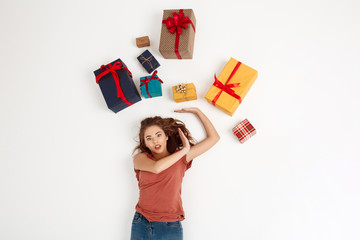 Young beautiful curly girl lying among gift boxes Shot from above Isolated