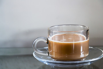 Hot coffee in glass cups and coffee beans on a glass table.