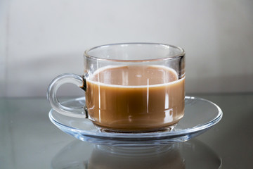 Hot coffee in glass cups and coffee beans on a glass table.