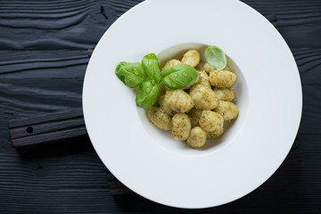 Gnocchi with basil pesto, black wooden surface, top view