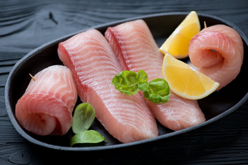 Closeup of marinated fillet of tilapia fish with lemon and basil