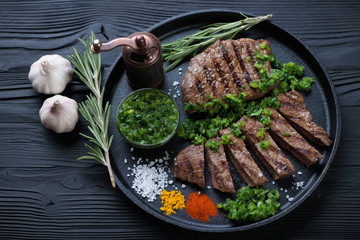 Frying pan with two barbequed rumpsteaks served with chimichurri