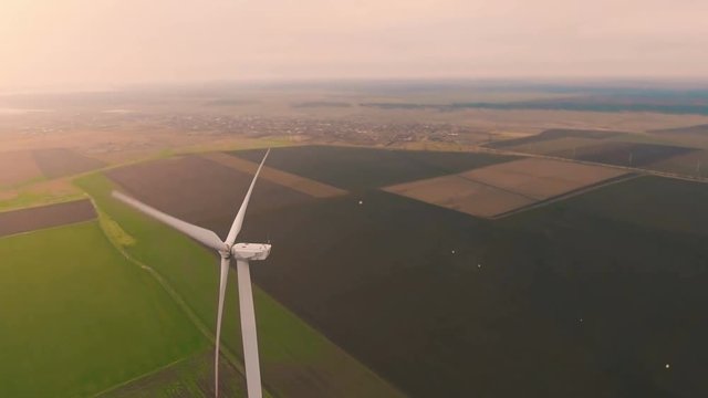Drone epic circling over wind turbine on green field at sunset .4K.