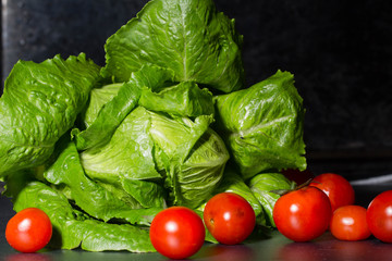 raw lettuce, red peppers and tomatoes on black background