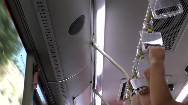 Close up of hands of people traveling travelling by public transport standing and holding onto hanging holders