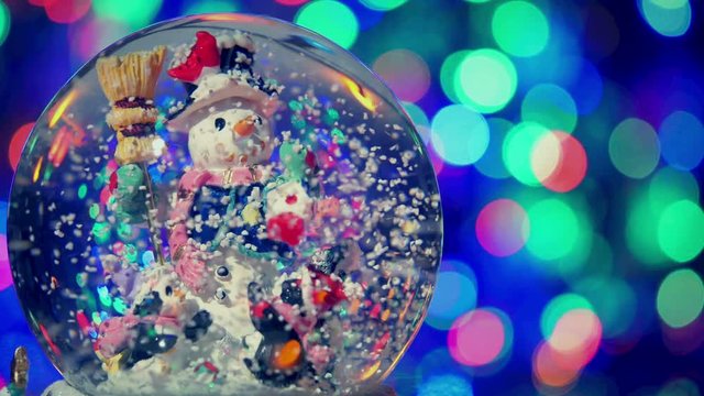 Christmas snow globe with snowman, with new year tree lights twinkling.
