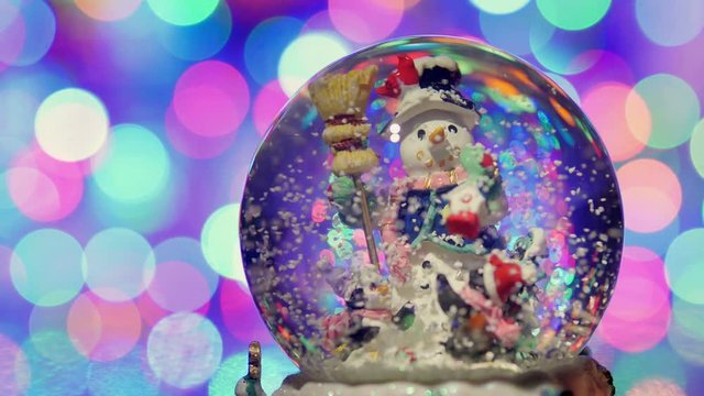 Christmas snow globe with snowman, with new year tree lights twinkling.
