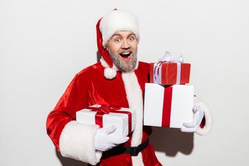 Cheerful man santa claus standing and holding present boxes