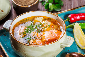 Fish soup with salmon and shrimps, dill, potatoes, lemon, peppers and bread on dark wooden...