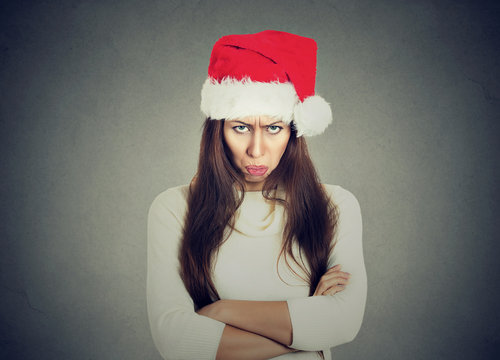 Upset woman in santa claus hat arms crossed looking at you