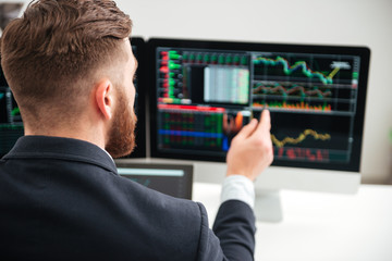 Back view of businessman woking with graphs on computer
