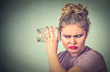 Nosy woman with glass jar listens to gossip behind the wall
