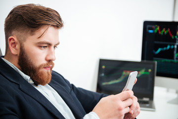 Concentrated businessman working and using cell phone in office