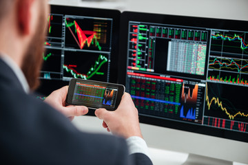 Back view of businessman working with computer and smartphone