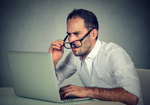 man with glasses having eyesight problems confused with laptop software