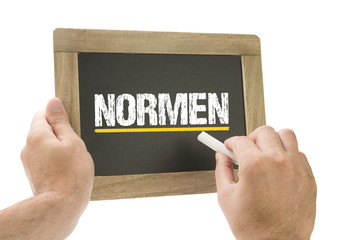 Normen / Hand schreibt auf Kreidetafel