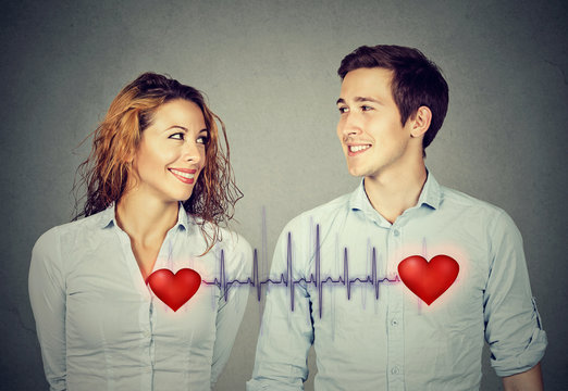 man woman looking at each other with red hearts linked by cardiogram