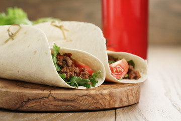 homemade tortilla with beef, frillice and vegetables and drink on wooden board, shallow focus