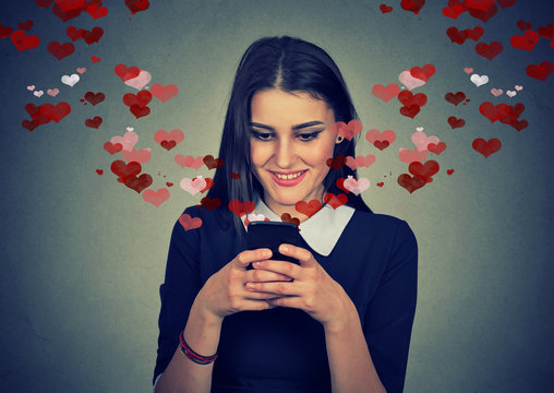 woman sending love message on mobile phone hearts flying away