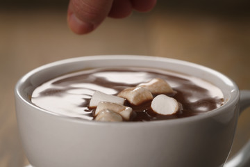 Fototapeta na wymiar put marshmallows in cup of homemade hot chocolate , shallow focus