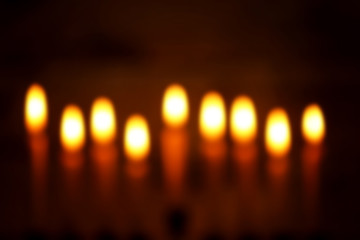 Blurred view of nine burning candles on dark background. Hanukkah concept
