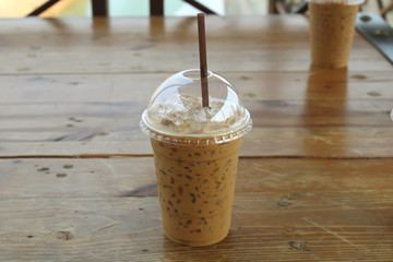 Iced coffee with straw in plastic cup on wood tables