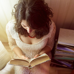 girl reads a book by the light of lamp. View from the top down