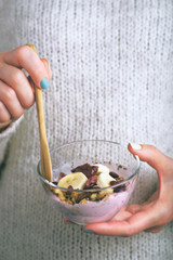 Glass bowl with yogurt and granola in the woman hands