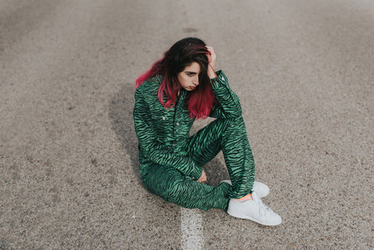 Teen girl sitting on asphalt road