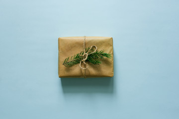 Handmade craft gift box on mint background with a branch of spruce