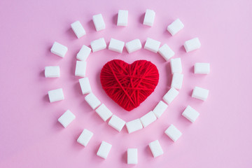 Red heart and sugar cubes on a pink background