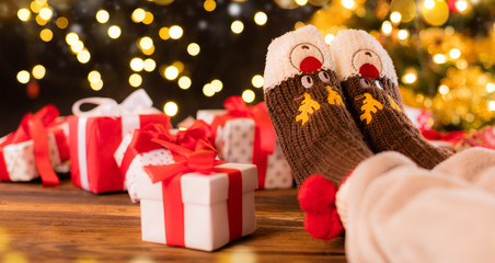 Woman feet in woollen socks, blur Christmas background