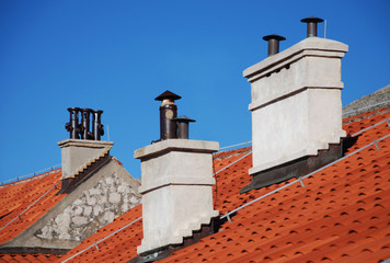 Tres chimeneas sobre tejados rojos