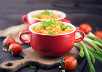 White beans in tomato sauce in a red ceramic bowl on rustic wood